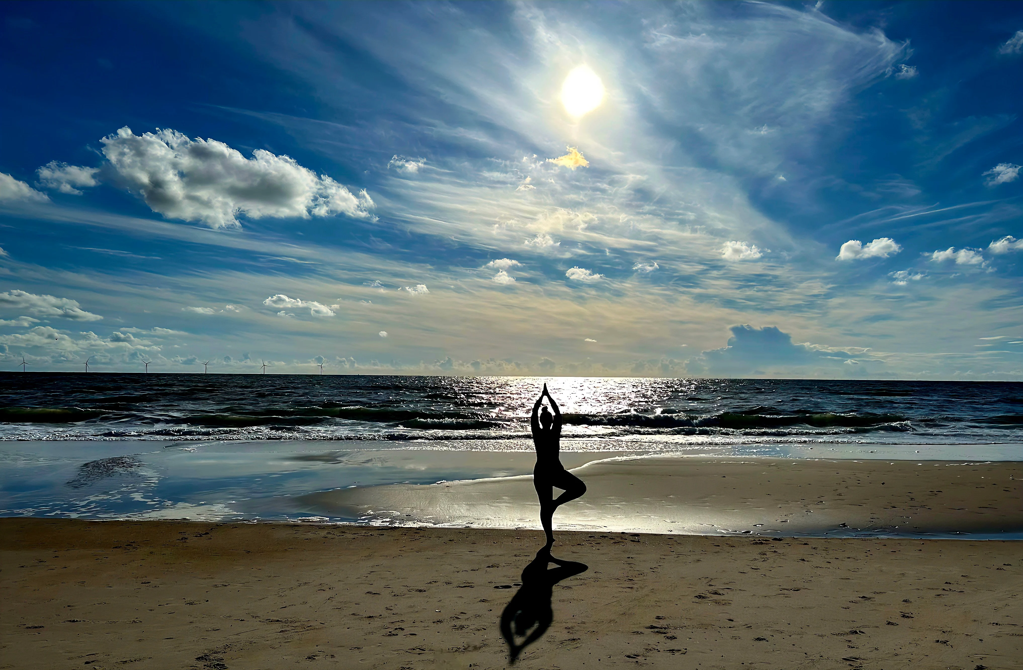 Person in Yoga-Baumhaltung am Strand vor weitem Himmel und Meer — Sinnbild für Balance, Ruhe und Achtsamkeit